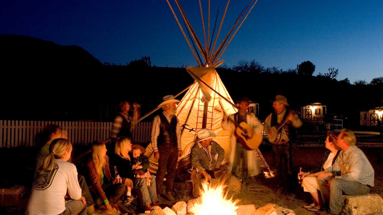 Guests around a campfire beside a tipi at Grand Canyon Western Ranch at night