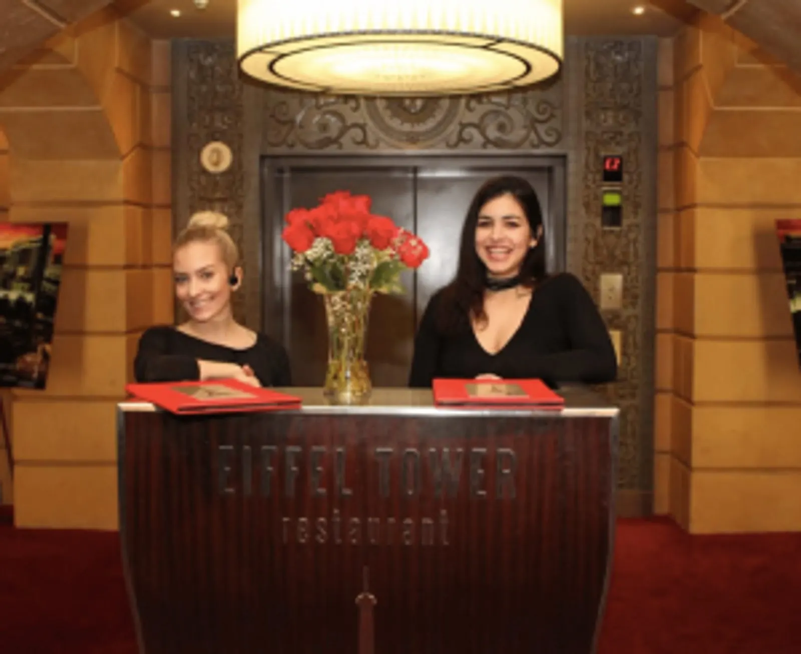 Two champagne glasses and roses at a window table overlooking the Las Vegas Strip