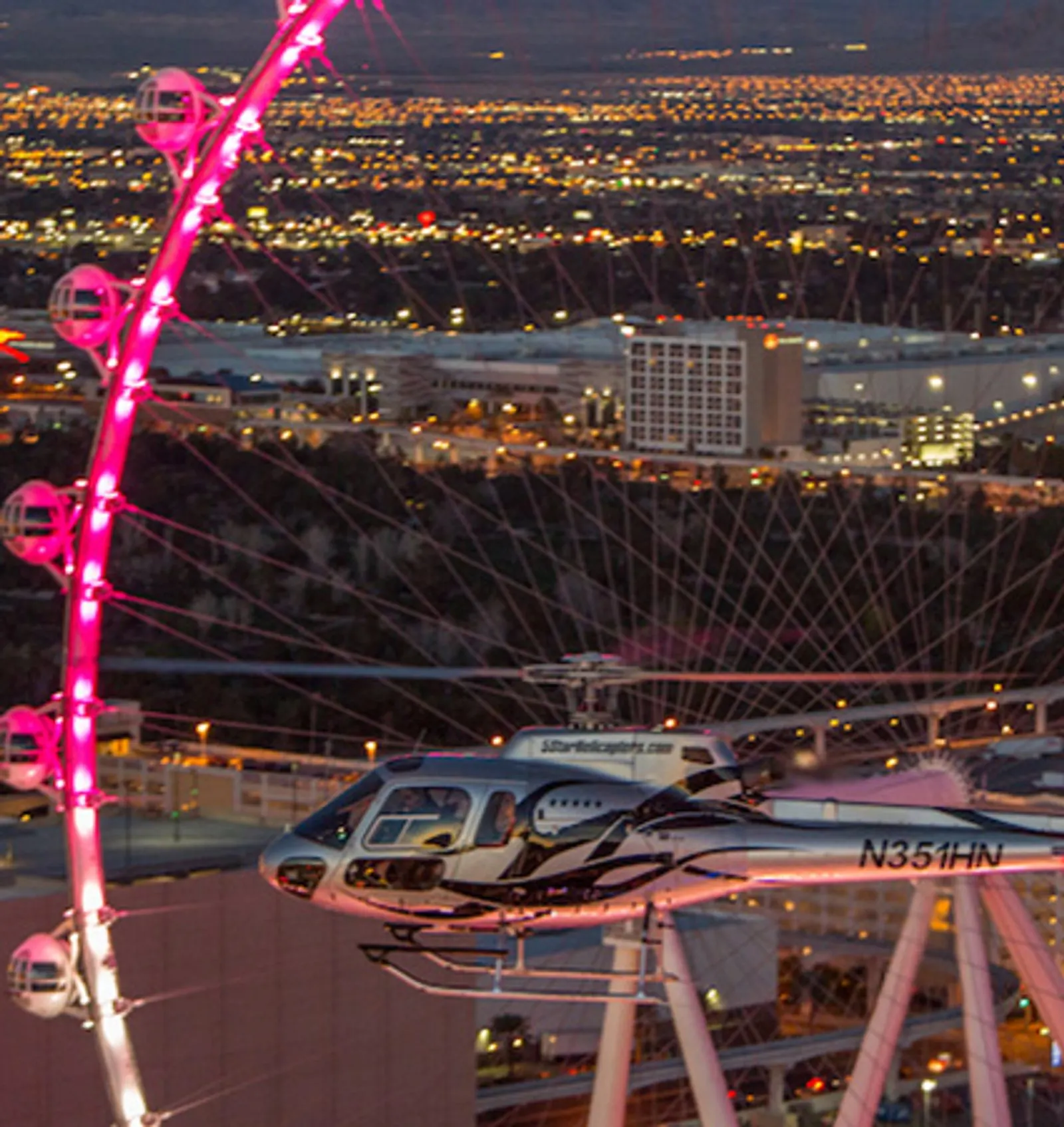 Helicopter passing the High Roller observation wheel at night