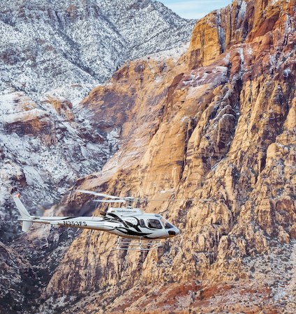 Helicopter flying past the striped cliffs of Red Rock Canyon in full daylight