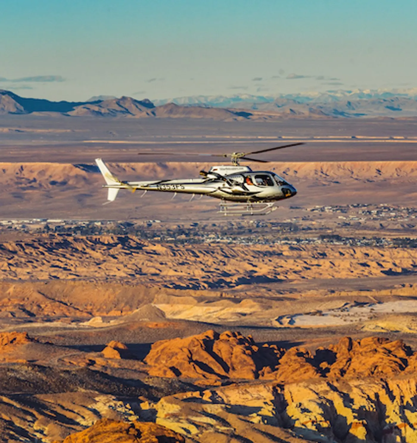 Helicopter crossing the open Mojave Desert toward distant mountains